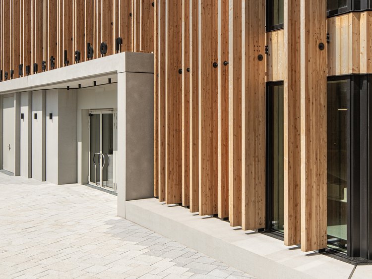 Front view of the main entrance area of a building with a wooden façade and clearly defined entrance area.
